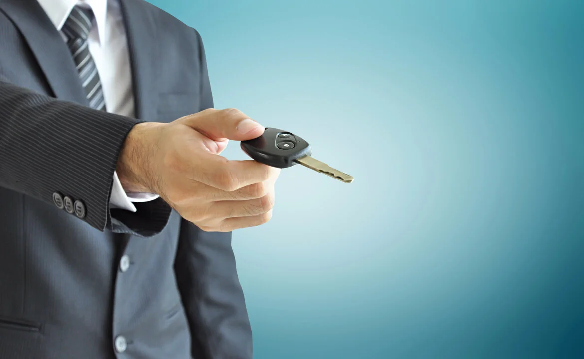 Businessman hand giving a car key - car sale & rental business concept