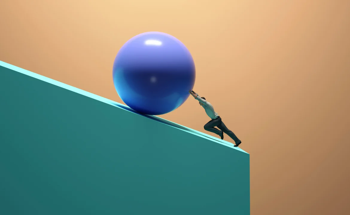 a man pushing a blue ball uphill