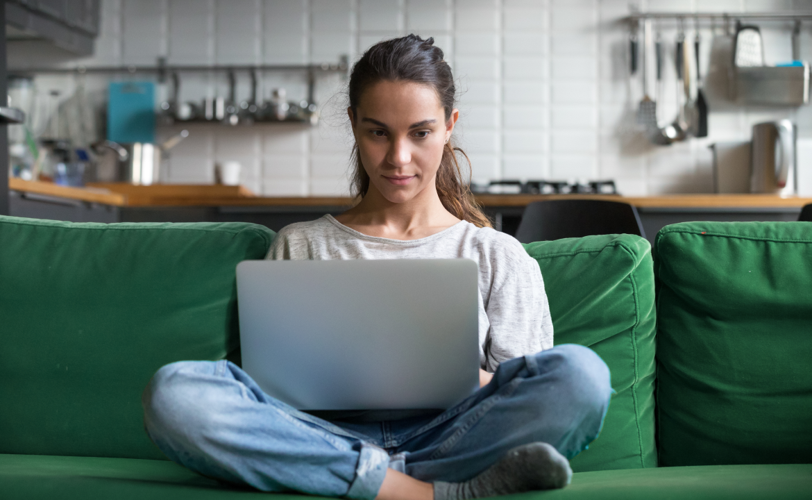 a woman sitting on a couch with her legs crossed with a laptop